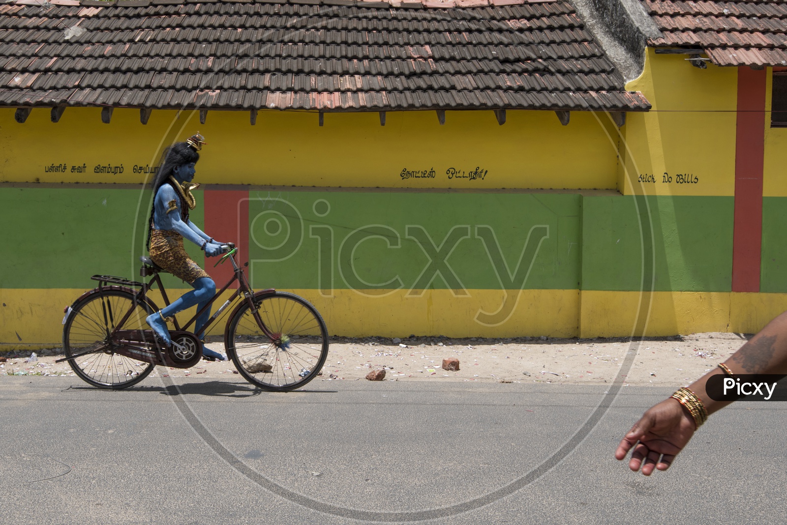 An Indian Boy In Lord Shiva Getup Riding a Bicycle