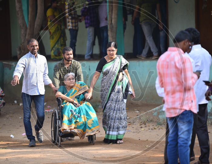 An old Woman Being Taking To Voting Booth in a Wheel Chair for Casting Her Vote In Telangana Pachayath Elections 2019