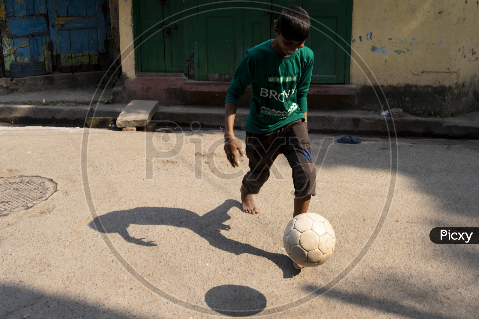 Indian kid playing football in streets of Kolkata