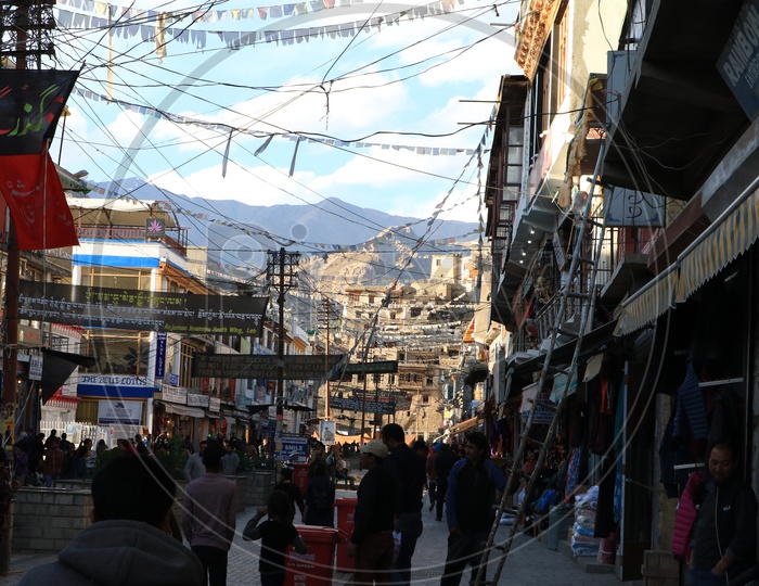 People walking in the streets of Leh and leh mountains in the background