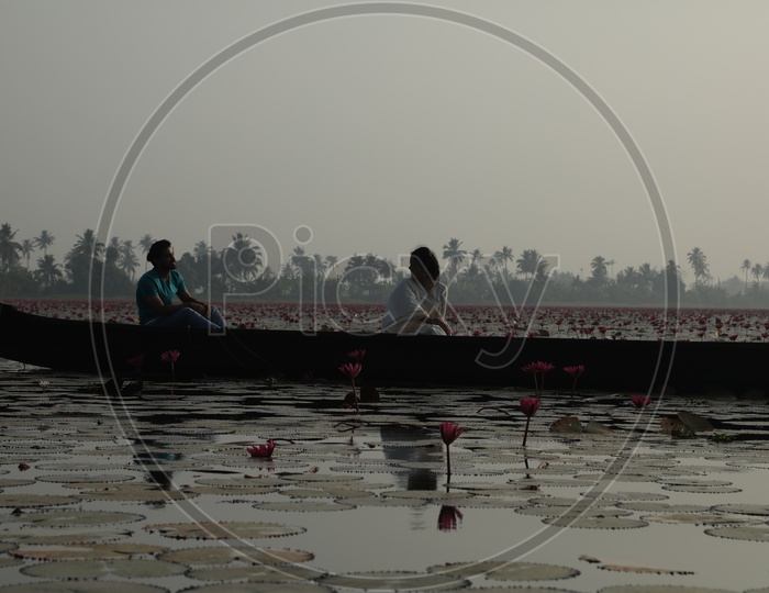 people travel in boat on lake with lotus flowers