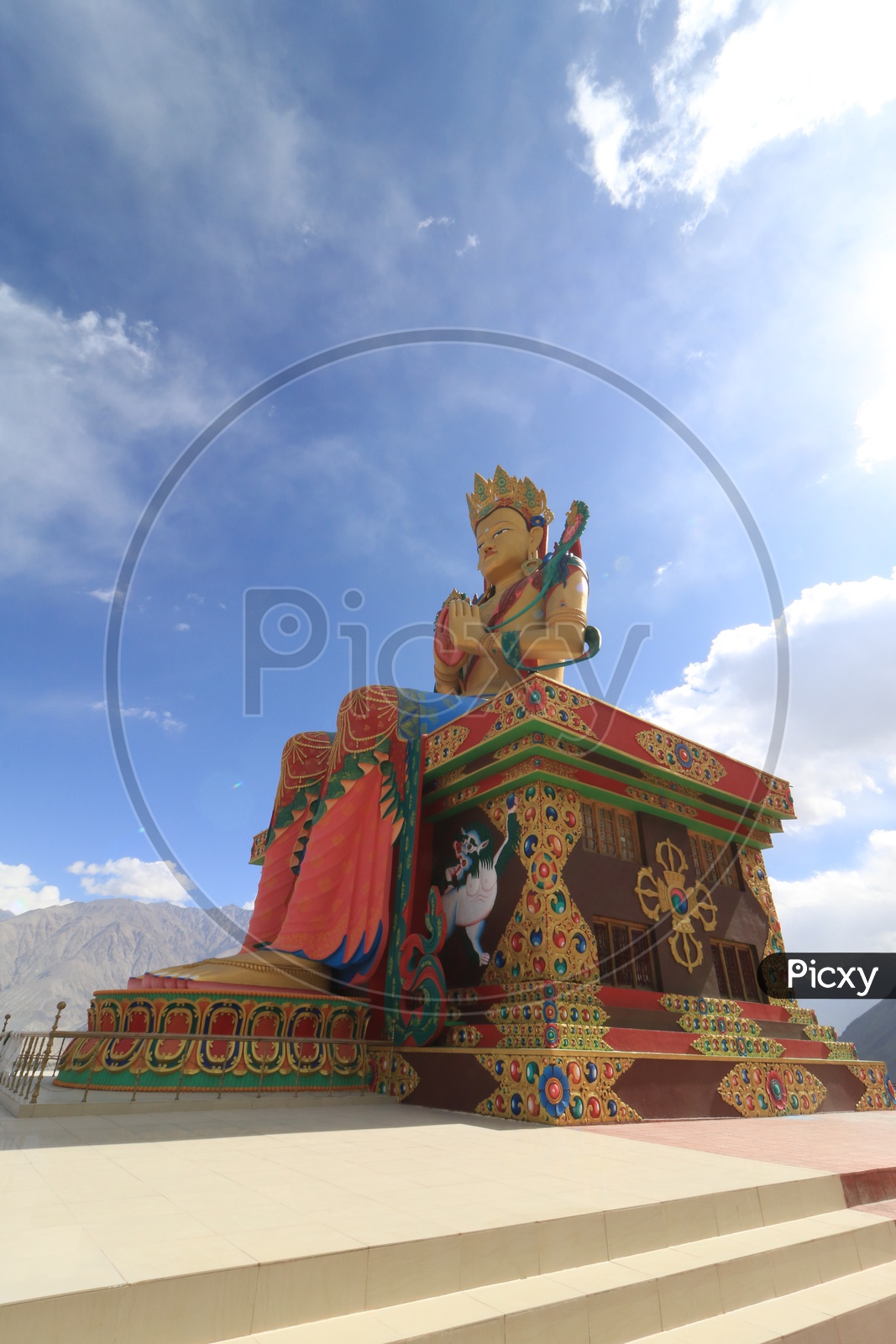 Buddha Statue with leh mountains in the background and clouded sky