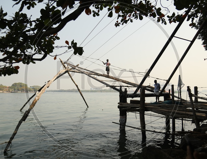 Man standing on the chinese fishing net by the water