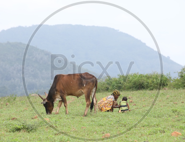 Women with a child and cow eating grass