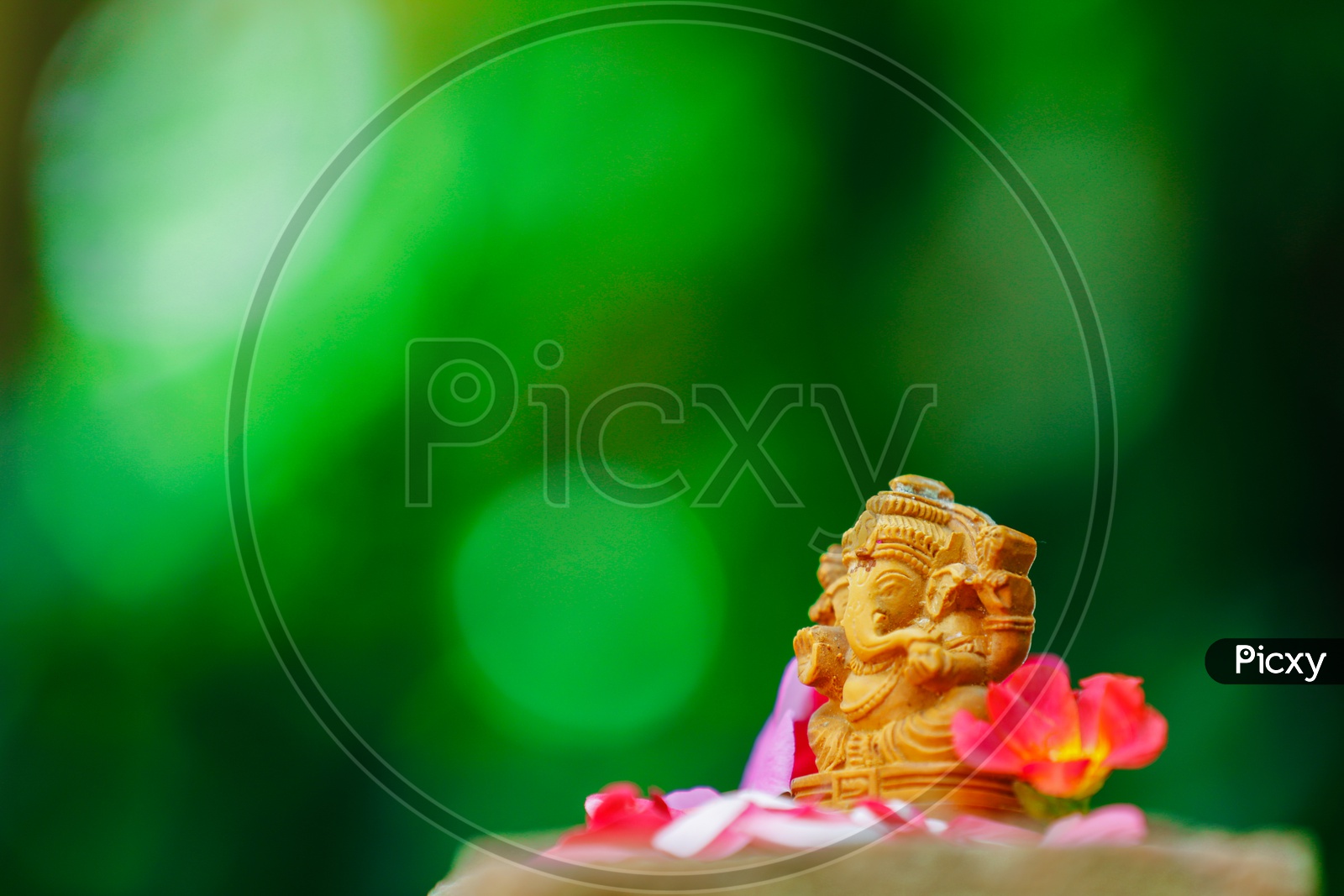 Lord Ganesh Idol  with  beautiful flowers in the foreground and greenery in the background