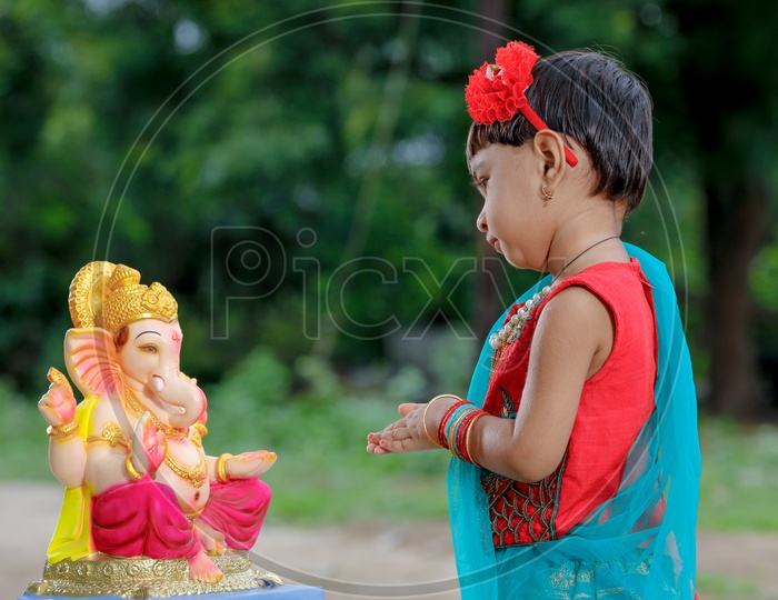Indian Girl Child Offering Prayer to Indian Hindu God Lord Ganesh