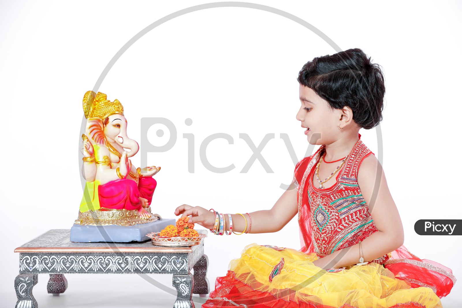 Indian Girl Child Offering Prayer to Lord Ganesh Statue On an Isolated White Background with Expression