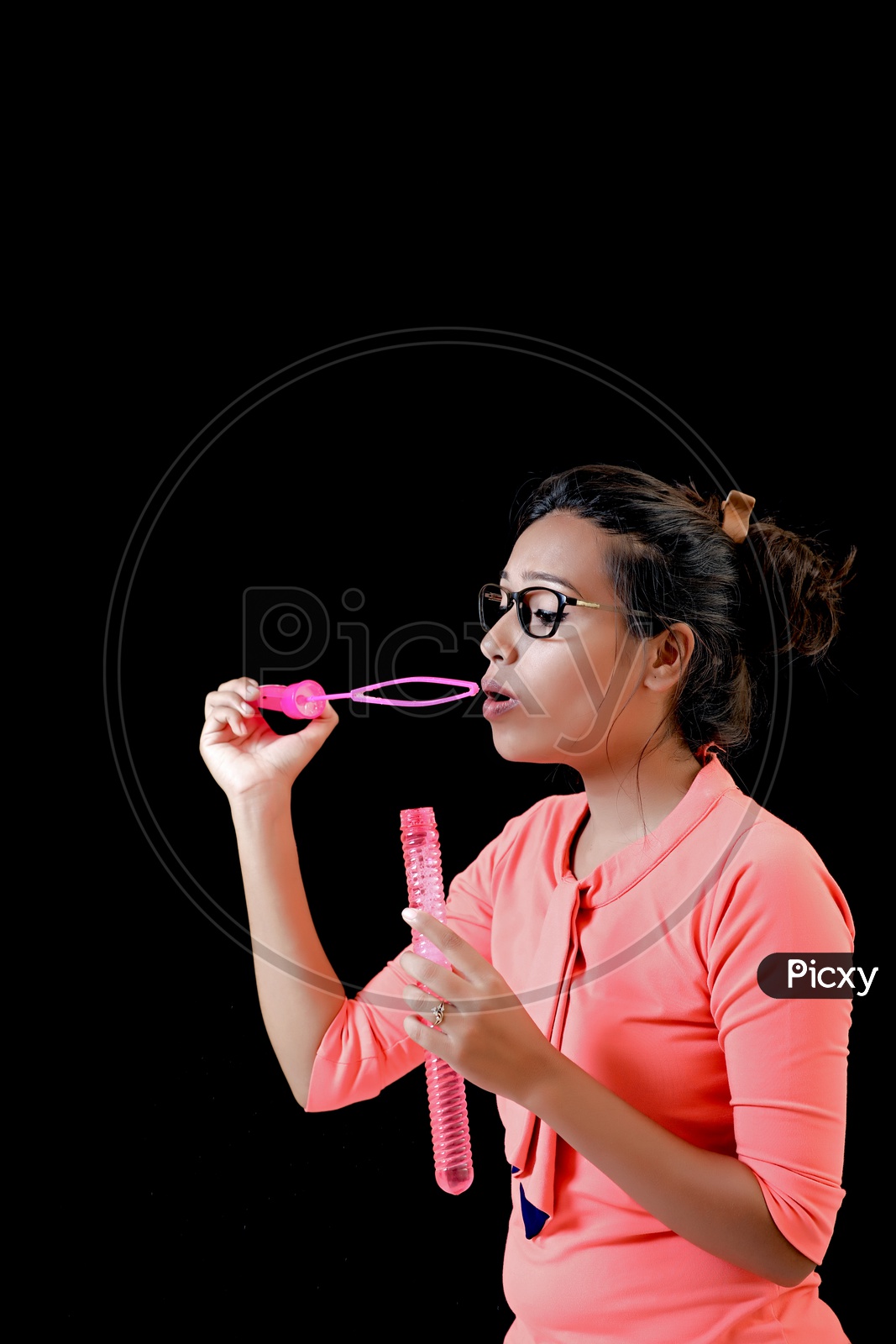 Indian Young  Girl Blowing Bubbles on an Isolated Black Background
