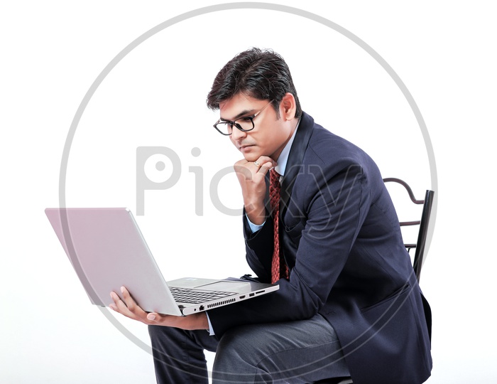 Indian Young Professional Man In Suite Holding Laptop in Hands  With an Expression on Face