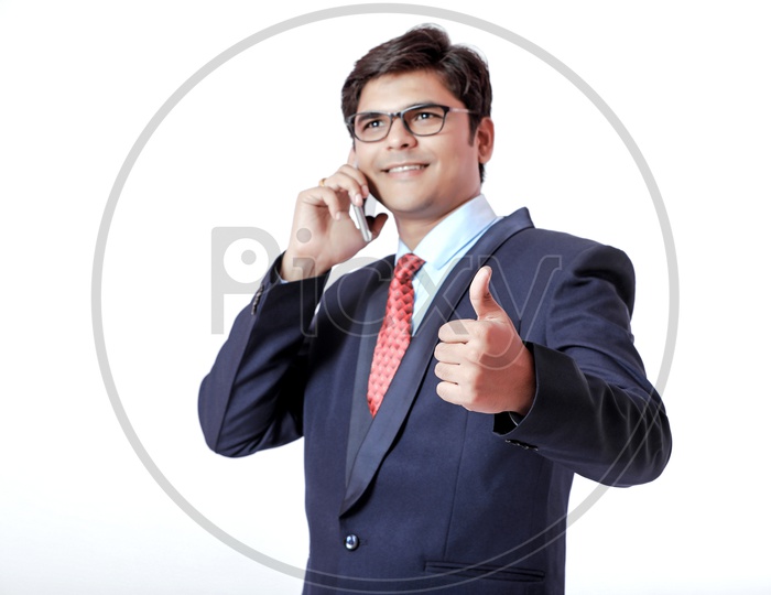 Indian Young Professional Man In Suite Speaking on Phone  with a Smile On Face  and with Gestures