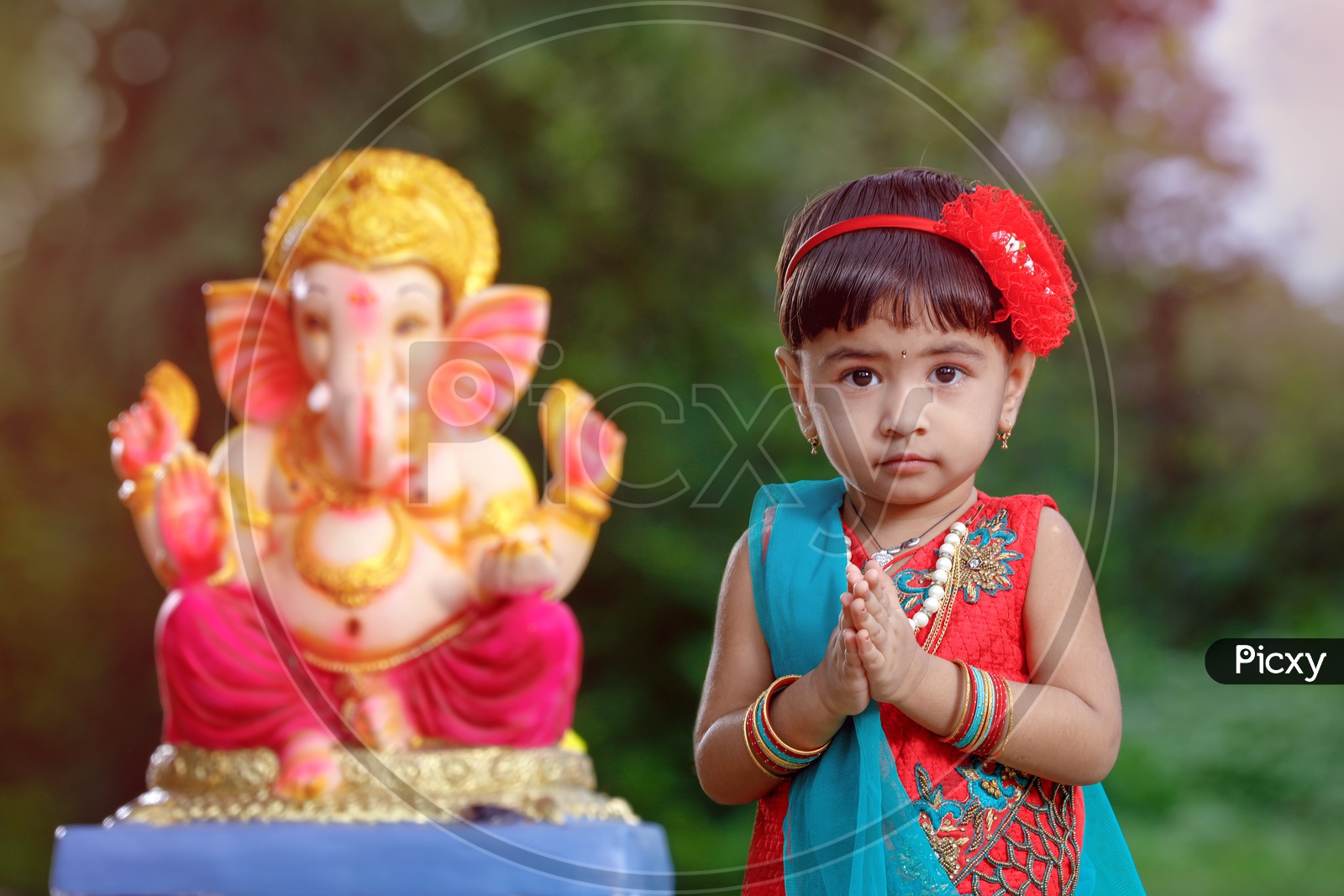 Image of Indian Girl Child Offering Prayer To Hindu Elephant Headed God