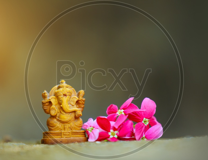 Lord Ganesh Idol  with  beautiful flowers in the foreground / Ganesha Idol