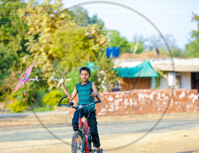 Indian Boy Playing With Kite while Cycling  in Rural India