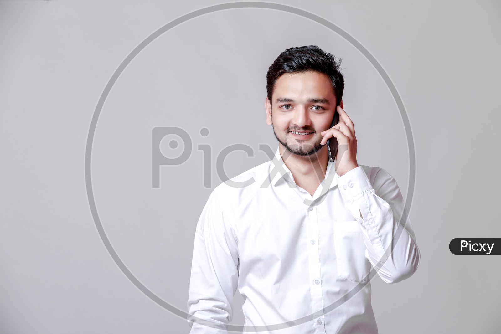 Indian Young Professional Man With a Smiling Face and Speaking in Mobile  On an Isolated White Background