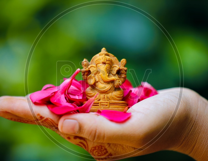 Ganesh Idol placed in palm and beautiful greenery in the background