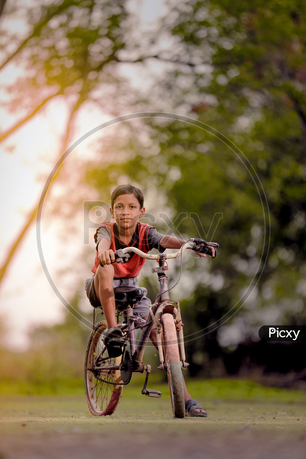Indian Boy Child Riding Bicycle in Rural India with a Smiling Face And Looking To Camera