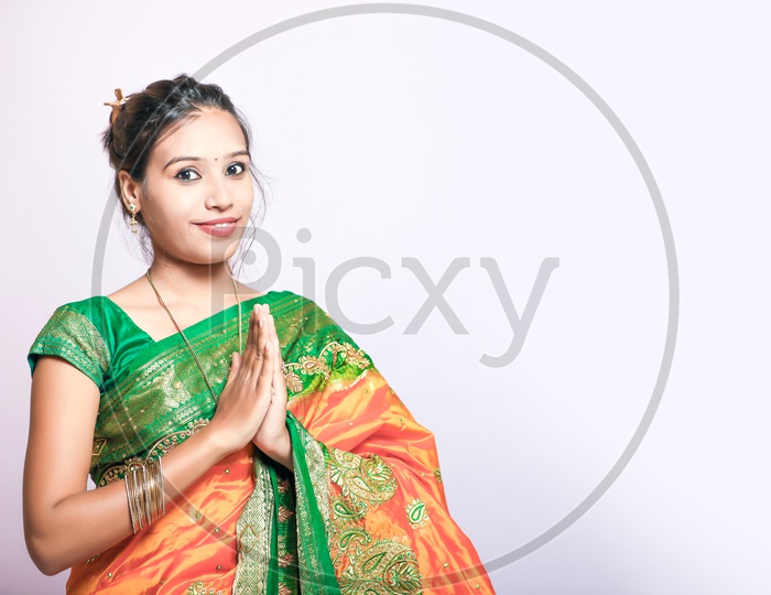 Indian Young Lady Wearing Saree and Saying Namaste Gesture with a Smiling Face on an Isolated White Background