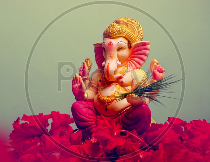 Ganesh Idol with red flowers in the foreground
