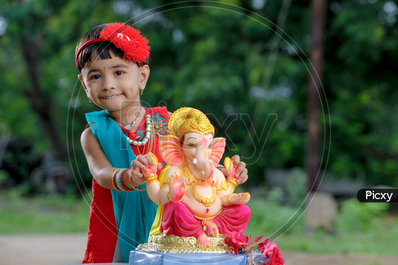 Indian Girl Child  with Hindu God Lord Ganesh Statue With Smiling Face