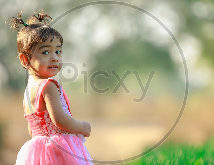 Indian Cute Girl Child Wearing Frock Playing in Paddy Fields  with Expression on face