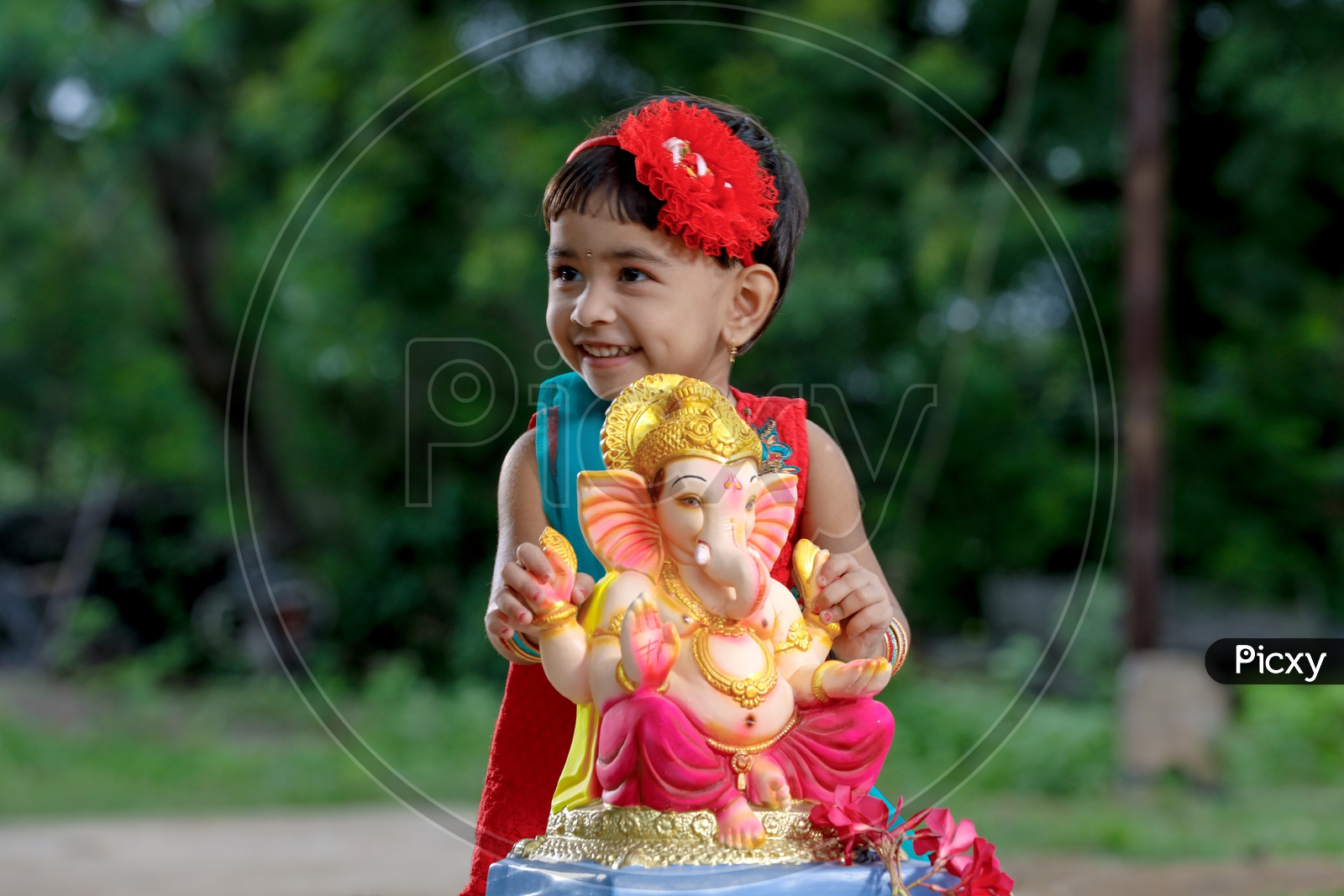 Indian Girl Child  with Hindu God Lord Ganesh Statue With Smiling Face