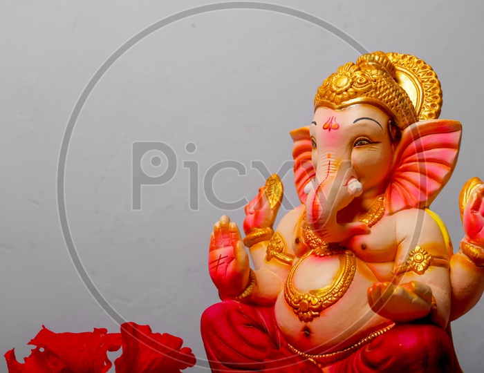 Ganesh Idol with red flowers in the foreground