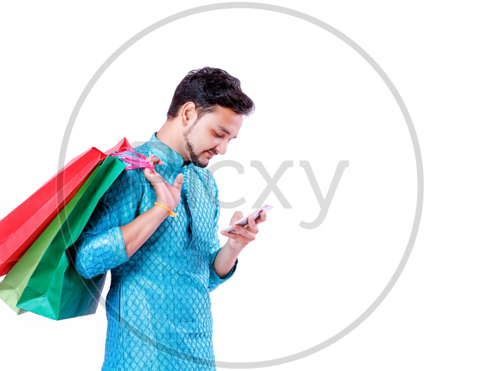 Portrait of a happy Indian Men carrying shopping bags  and looking into mobile with white background