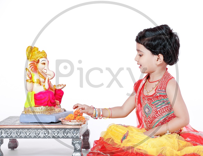 Indian Girl Child Offering Prayer to Lord Ganesh Statue On an Isolated White Background with Expression