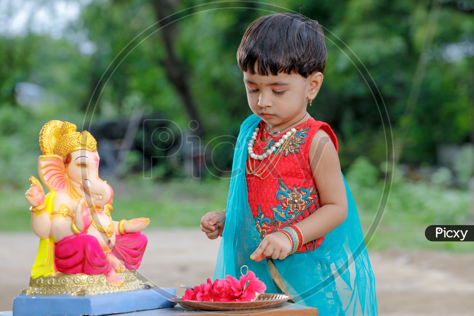 Indian Girl Child Offering Prayer to Indian Hindu God Lord Ganesh