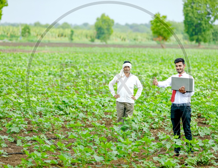 Indian Young Professional in Agricultural Field operating Laptop With Farmer