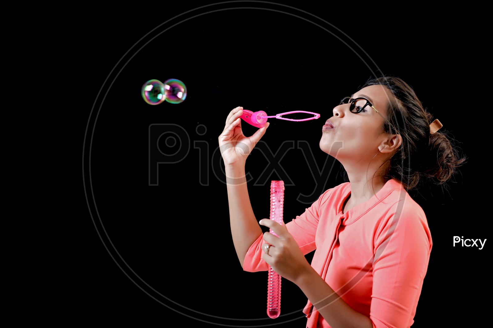 Indian Young  Girl Blowing Bubbles on an Isolated Black Background