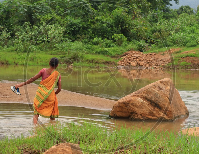 A Woman Crossing A Water Channel In rural Area
