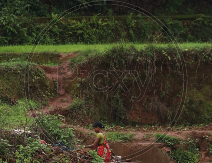 A Woman Washing Clothes By A Agricultural Field in Rural Village