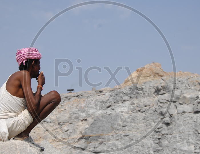 An Old Man Sitting on a Rocks of a Quarry