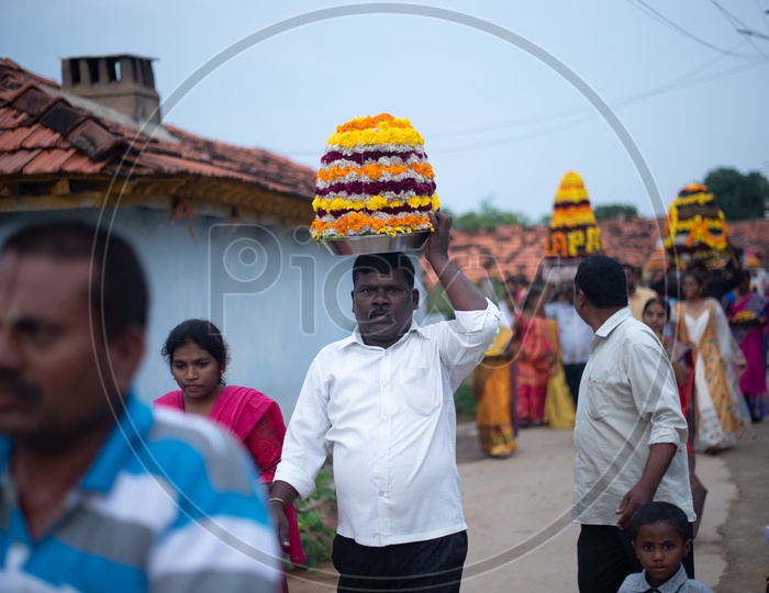 Men carry Bathukamma, a floral decoration  on Saddula bathukamma (pedda bathukamma) day in Telangana.