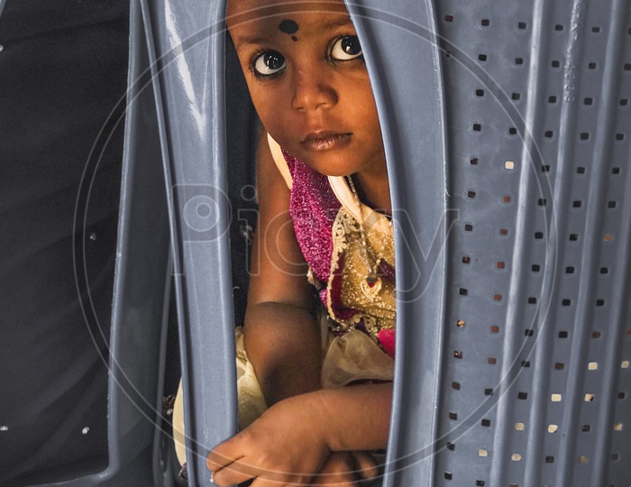 An Indian girl child peeping from a chair