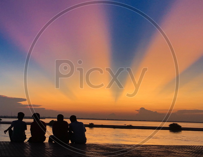 Silhouette of friends enjoying the sunset by the River Godavari