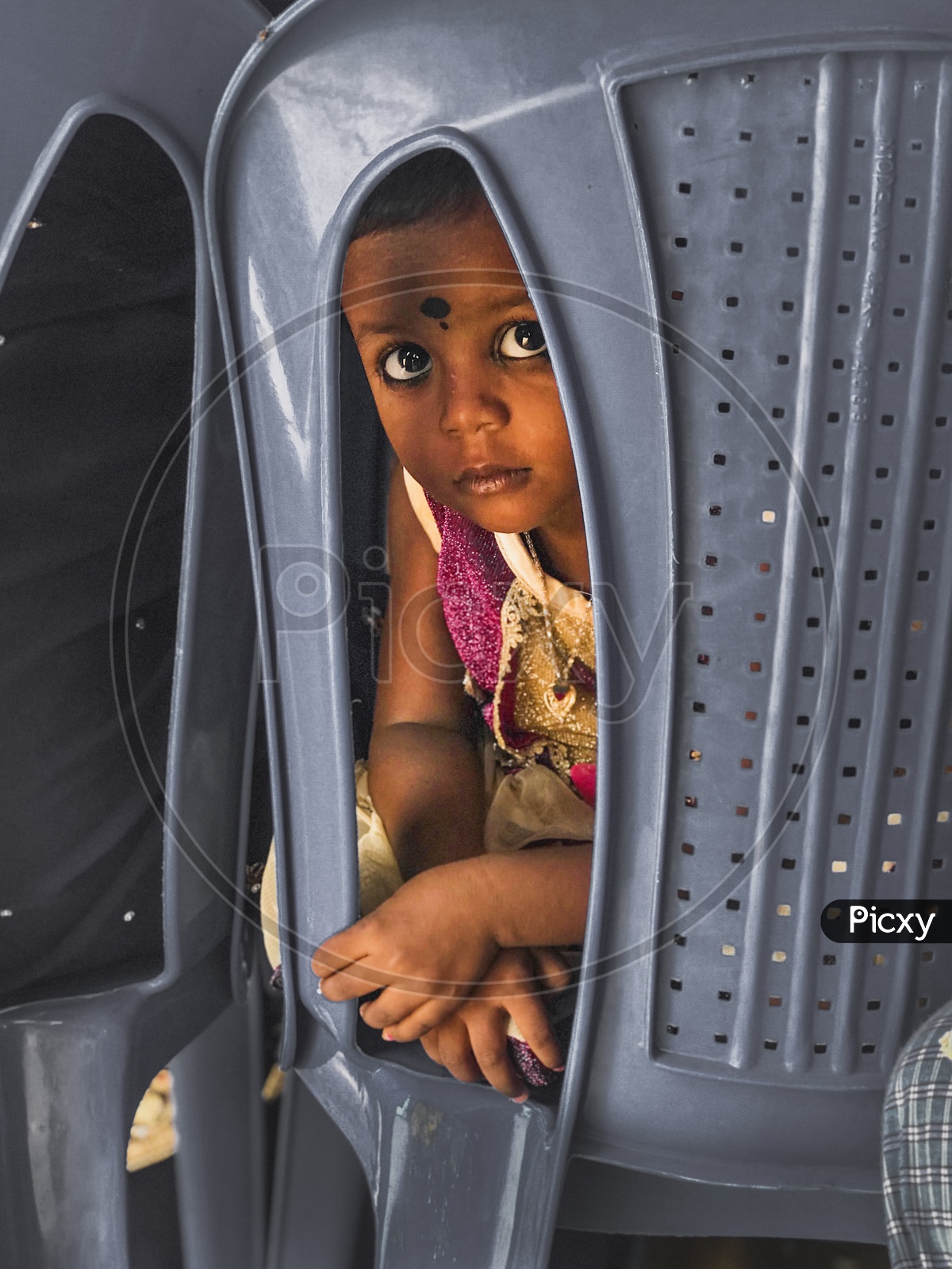 An Indian girl child peeping from a chair