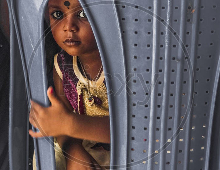 An Indian Girl child looking through the chair