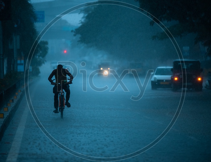 A Bicycle Rider Commuting In Heavy Rain near Shilparamam