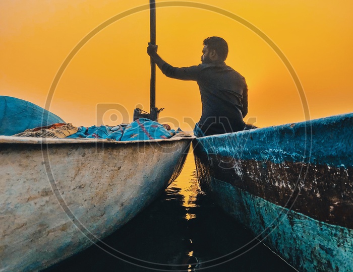Indian Man enjoying the sunset by the fishermen boats