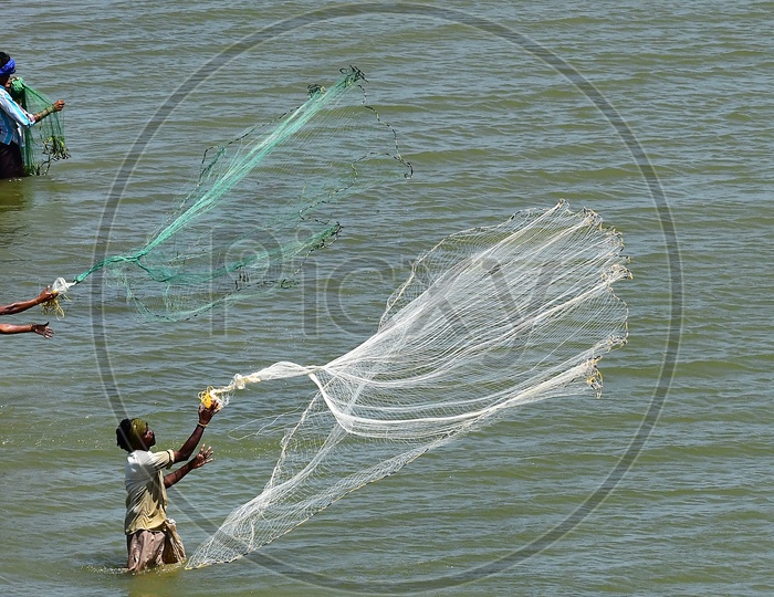 Image of Fisherman Throwing Fishing Nets into River Water For