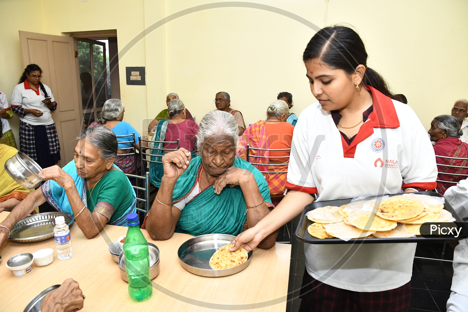 Young Girl Serving Food to Old People  In a Old-age Home