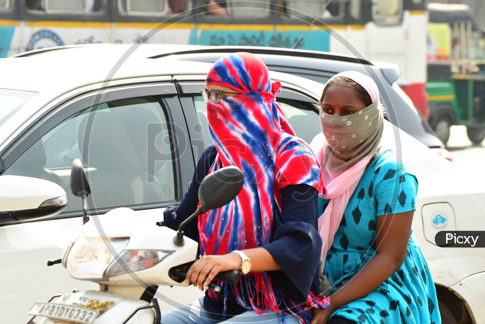 Indian women riding scooty with their faces covered with scarfs