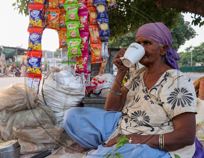 Indian Old Woman Making Tea On a Road side Pavement  and Drinking