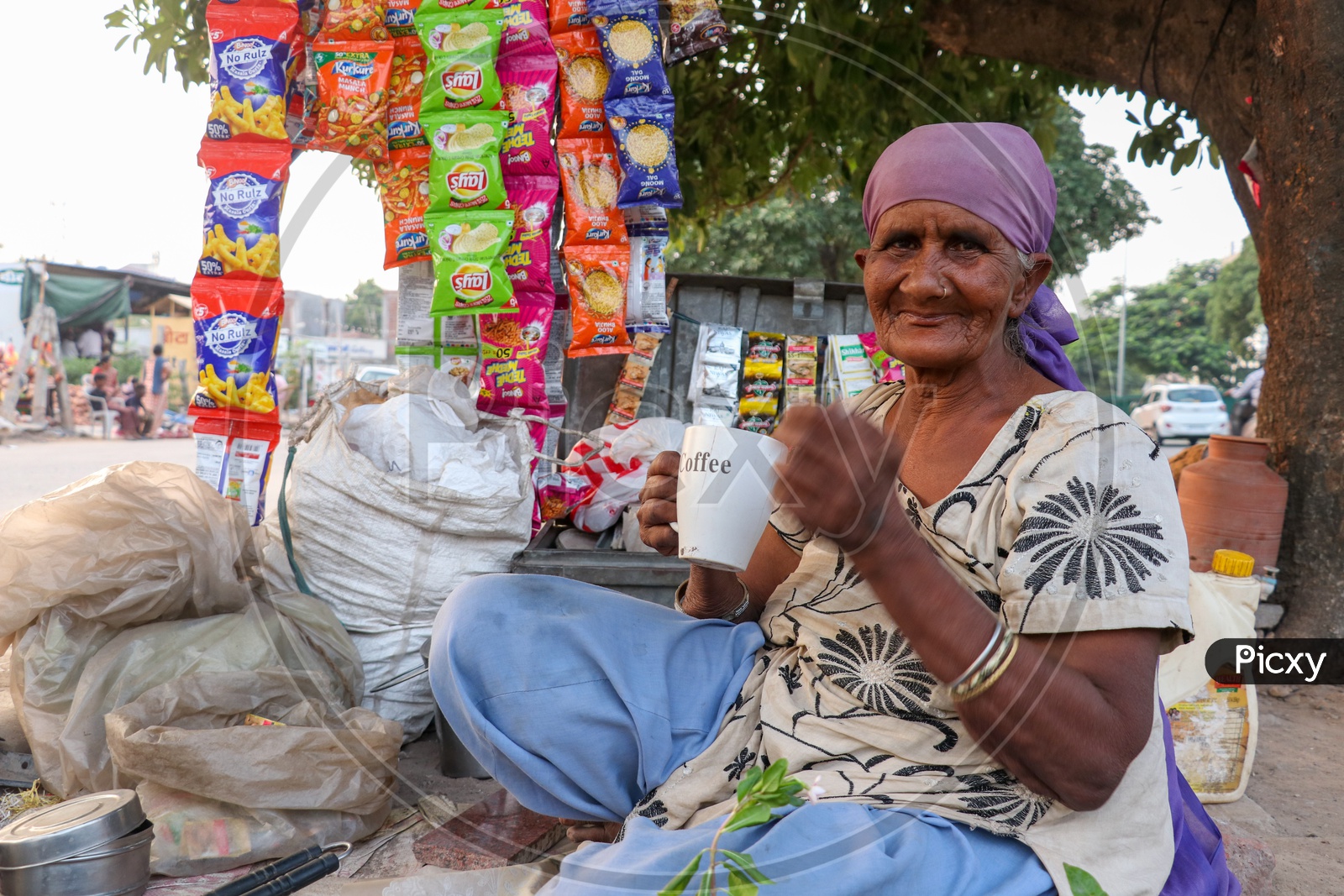An Old Woman Having Tea In a Cup At a Road Side vendor Stall