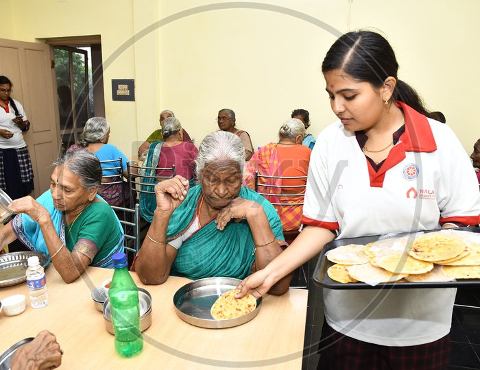 Young Girl Serving Food to Old People  In a Old-age Home