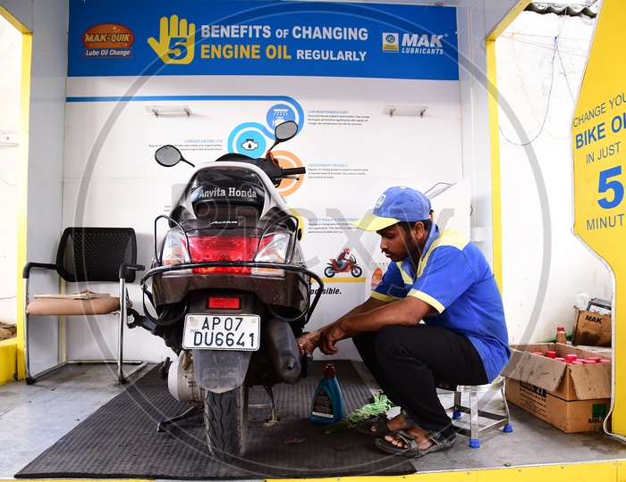 Mechanic Changing Engine Oil For a Scooty