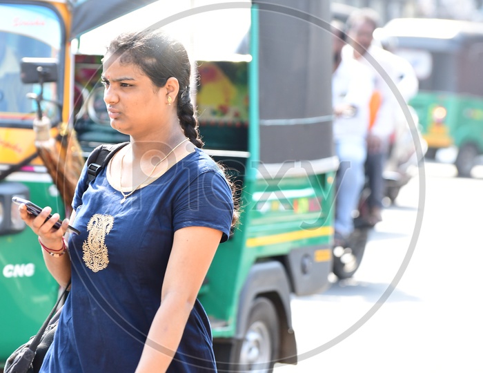 Indian girl walking holding a cellphone