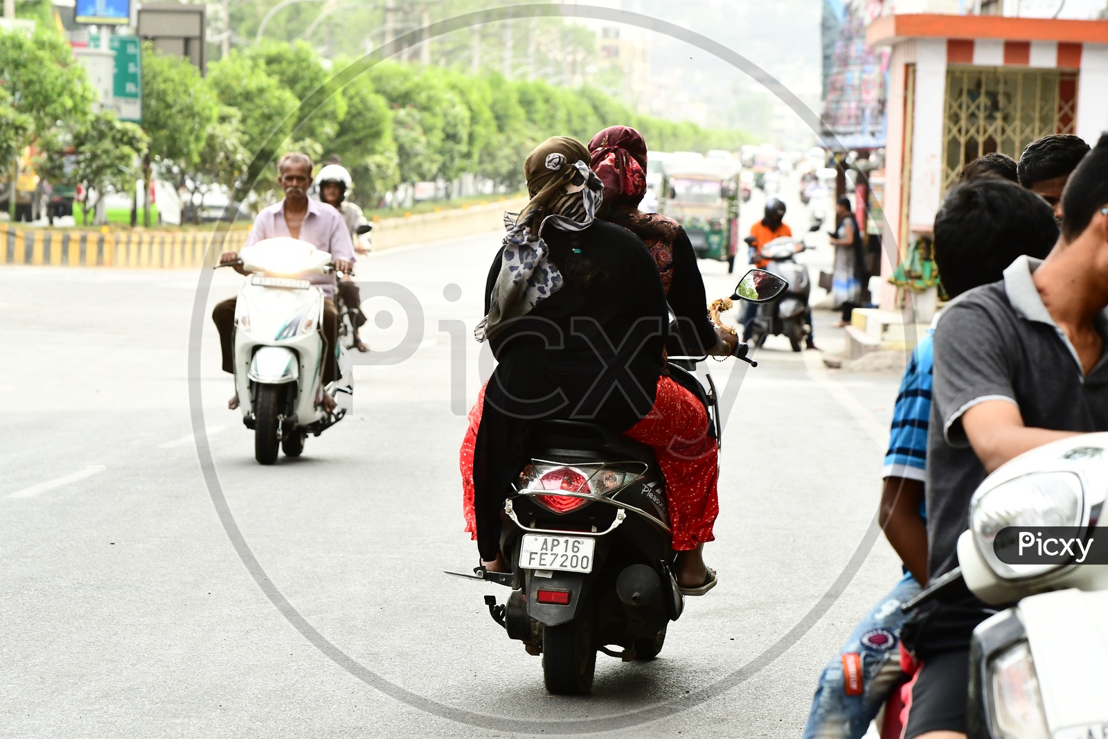 Indian Women wearing scarfs and riding scooters on the road